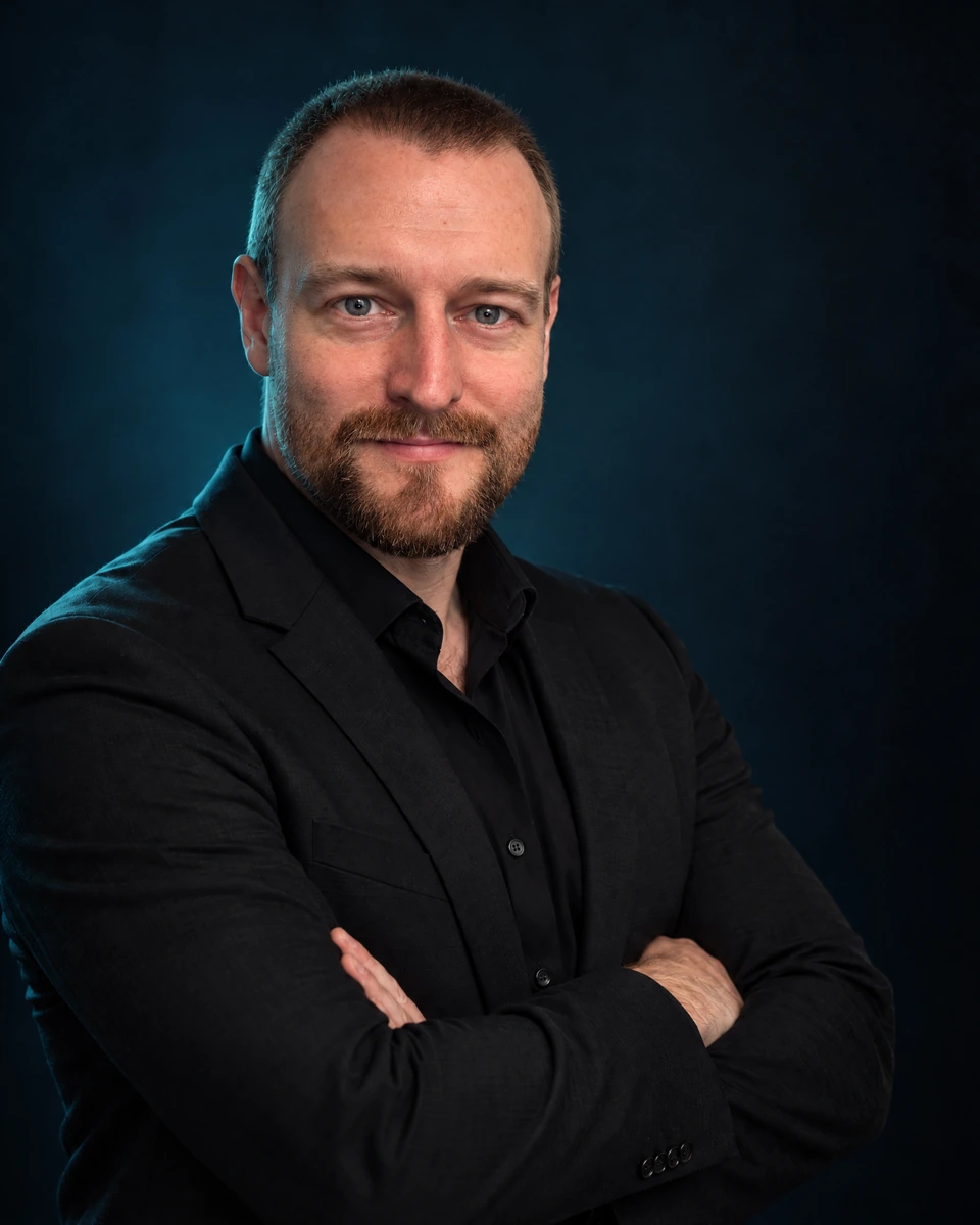 Radim Folvarčný v černém saku, s lehkým úsměvem a založenýma rukama